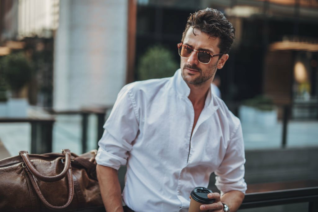 One young handsome businessman holding coffee and waiting for someone